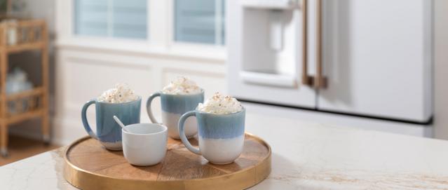 three mugs of hot cocoa with whip cream